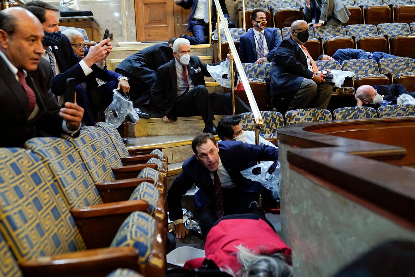 FILE - In this Jan. 6, 2021, file photo people shelter in the House gallery as rioters try to break into the House Chamber at the U.S. Capitol. Arguments begin Tuesday, Feb. 9, in the impeachment trial of Donald Trump on allegations that he incited the violent mob that stormed the U.S. Capitol on Jan. 6. (AP Photo/Andrew Harnik, File)