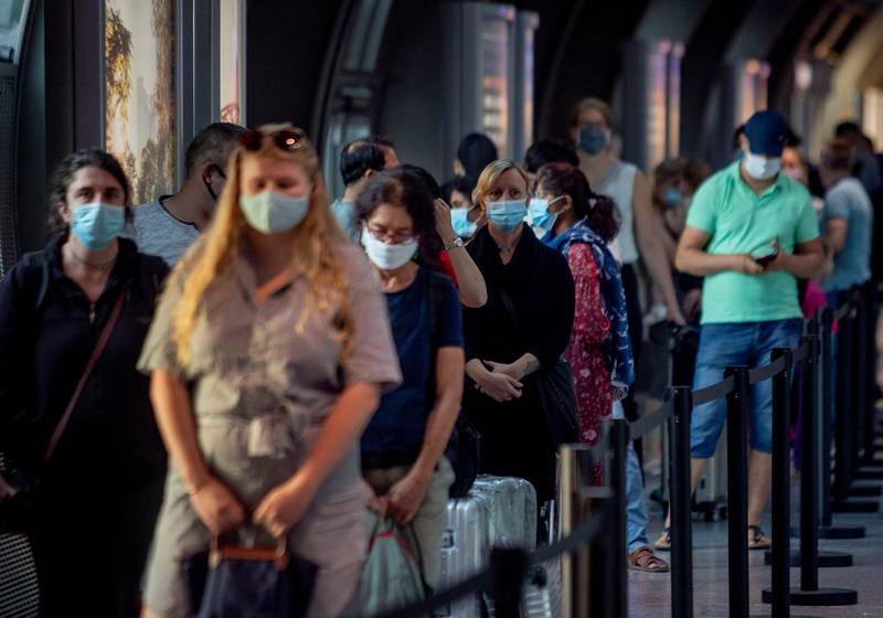 Passengers queue at a Corona test center at the airport in Frankfurt, Germany, Friday, Aug. 7, 2020. From Saturday on travelers coming back from one of the high-risk-countries have to do a Covid-19 test. (AP Photo/Michael Probst)