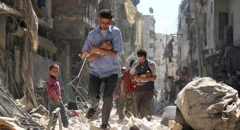Menn bærer små babyer ut av ruinene i Aleppo i september i år. Dette AFP-bildet er blitt kåret til et av årets bilder, tatt av Ameer Alhalbi.