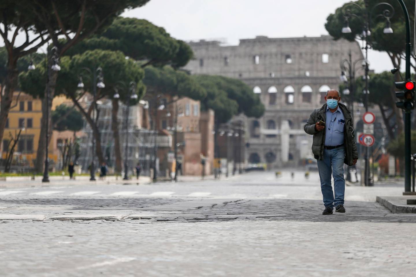 A man walks along an empty road following Italy's lockdown due to coronavirus emergency as the ancient Colosseum stands out in background, in Rome Sunday, March 29, 2020. The new coronavirus causes mild or moderate symptoms for most people, but for some, especially older adults and people with existing health problems, it can cause more severe illness or death. (Cecilia Fabiano/LaPresse via AP)