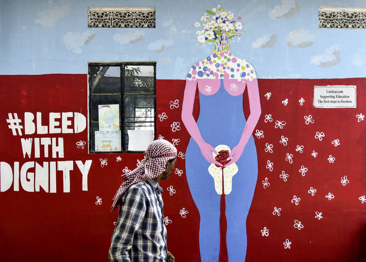 En mann går foran et veggmaleri om menstruasjon i India i 2019.