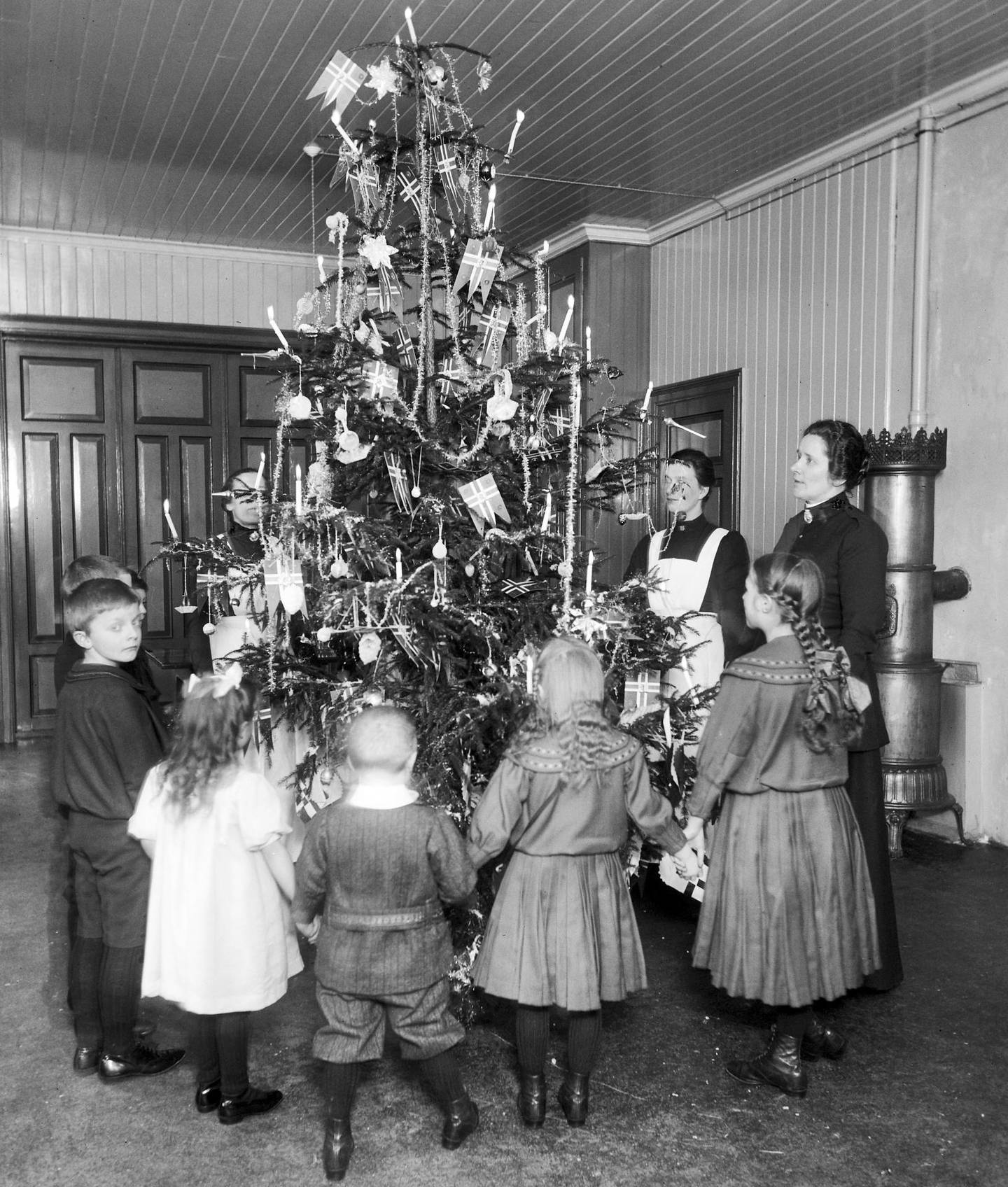 Juletreet tennes på Frelsesarmeens barnehjem i 1911. Gjennom skoler og institusjoner ble juletreet en vanlig tradisjon i siste halvdel av 1800-tallet. Foto: Anders B. Wilse, Oslo Museum