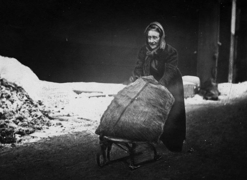 «Gamlemor henter selv sin kokssæk». En gammel kvinne frakter en kokssekk på en kjelke i Hausmannsgate fra Provianteringsrådets dyrtidshjelp i 1919.