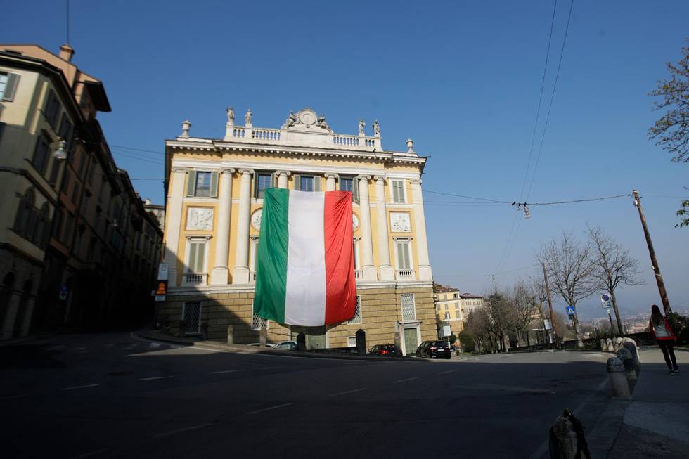 A giant flag of Italy hangs from the facade of Palazzo Medolago Albani in Bergamo Alta, the top part of the city, in Bergamo, one of the cities most hit by the coronavirus outbreak in northern Italy, Tuesday, March 17, 2020. For most people, the new coronavirus causes only mild or moderate symptoms. For some it can cause more severe illness, especially in older adults and people with existing health problems. (AP Photo/Luca Bruno)