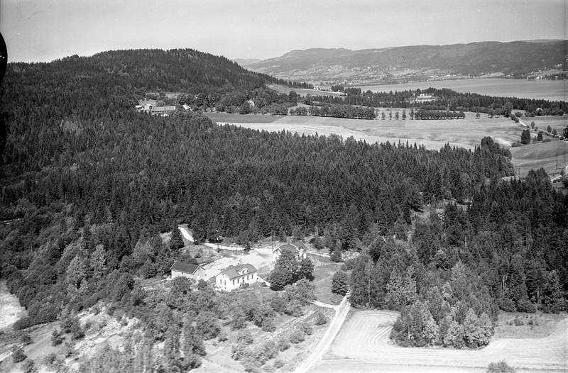 Eikhaugen skole i 1955, med gården Store Solum på Åskollen i bakgrunnen. Skolebygningene ligger i dag ved industriområdet ved Eikhaugen. 