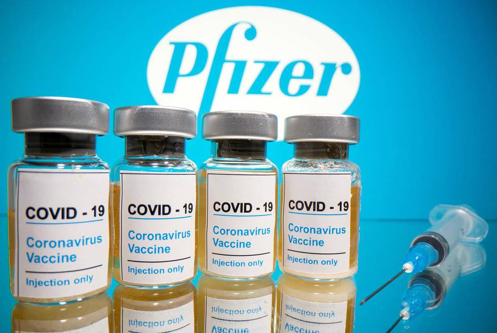 FILE PHOTO: Vials with a sticker reading, "COVID-19 / Coronavirus vaccine / Injection only" and a medical syringe are seen in front of a displayed Pfizer logo in this illustration taken October 31, 2020. REUTERS/Dado Ruvic/Illustration/File Photo