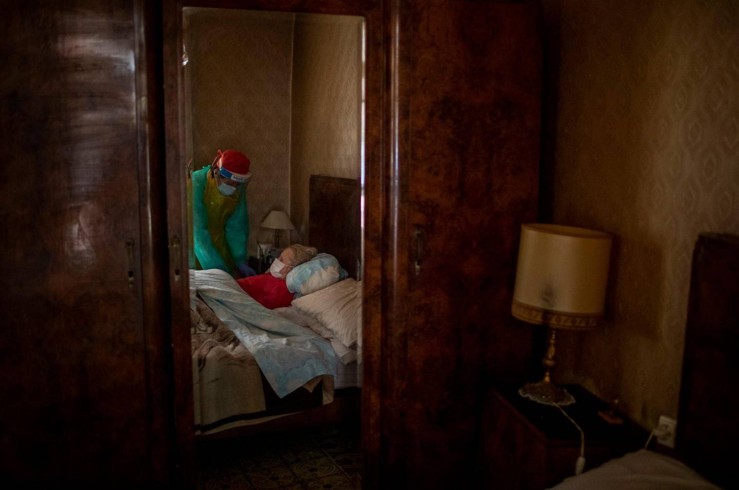 Josefa Ribas, 86, who is bedridden and suffers from dementia, is attended to by nurse Laura Valdes during a home care visit in Barcelona, Spain, on April 7, 2020. Ribas' husband, Jose Marcos, fears what will happen if the coronavirus enters their home and infects them. "I survived the post-war period (of mass hunger). I hope I survive this pandemic," he said. (AP Photo/Emilio Morenatti)