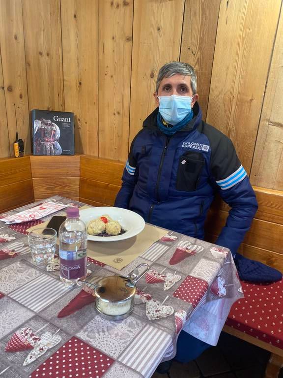 Denis Rocchi sitter ved et bord med tallerken og mat foran seg. Han har på seg munnbind.