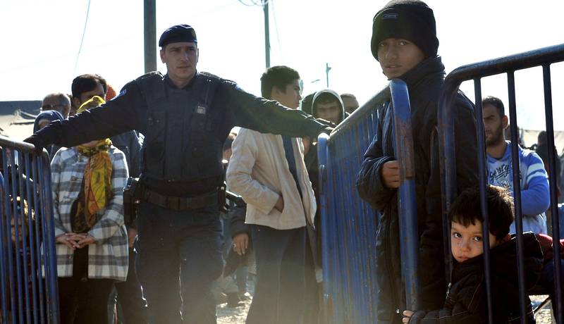 En kroatisk politimann holder vakt mens flyktninger og migranter står i kø for å komme inn i en transittleir i Slavonski. De vil videre til Slovenia og nordover derfra. FOTO: ELVIS BARUKCIC/NTB SCANPIX