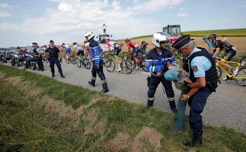 Cycling - Tour de France - The 218-km Stage 16 from Carcassonne to Bagneres-de-Luchon - July 24, 2018 - Police officers carry a protester off the road as the peloton passes. REUTERS/Stephane Mahe