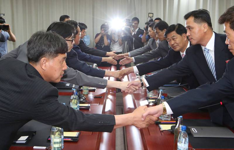 Medlemmer av det sørkoreanske gjenforeningsdepartementet håndhilser på nordkoreanske motparter under samtaler på deres felles samarbeidsfabrikk Kaesong i Nord-Korea i 2014. Etter en prøvesprengning fra Nord-Korea, stengte Sør-Korea fabrikken i fjor, men den nye presidenten vil gjenåpne den.