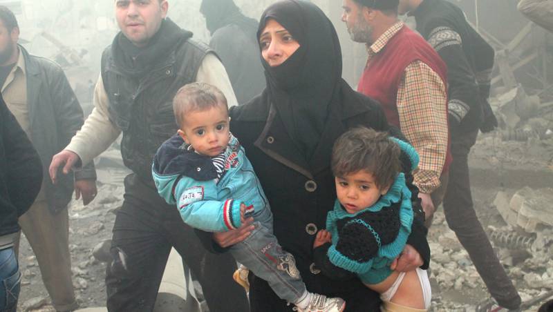 Fem år med krig: Det har vært kamper i Aleppo i mange år. En syrisk kvinne flykter fra luftangrep sammen med barna sine i Aleppo i 2013. 