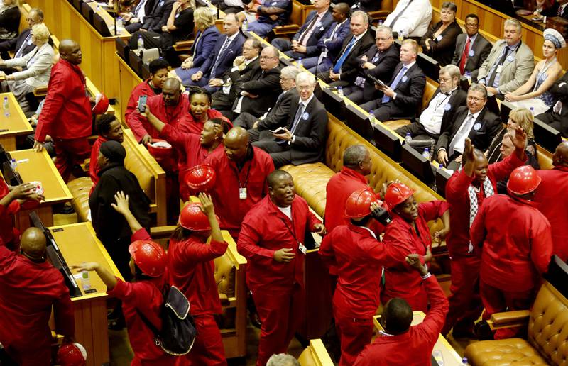Julius Malema (i midten) og hans partifeller i Economic Freedom Fighters uttrykte seg nok en gang på en utradisjonell måte i nasjonalforsamlingen, da president Zuma skulle tale. Zuma er i hardt vært både for landets økonomi og for skandaler rundt sin egen person. FOTO: SCHALK VAN ZUYDAM/NTB SCANPIX