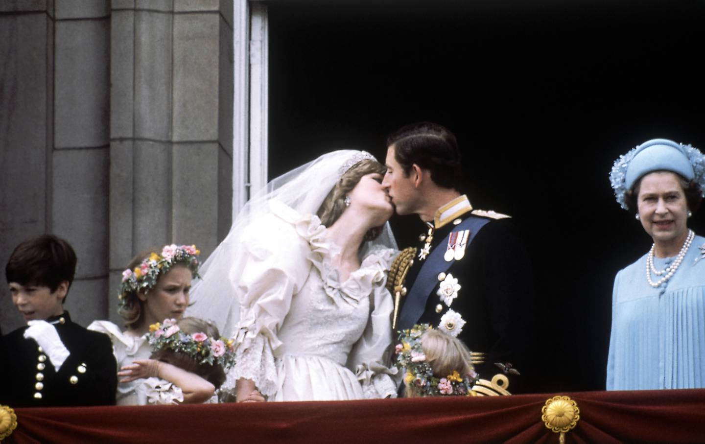 Prinsesse Diana og prins Charles deler et kongelig kyss på balkongen til Buckingham Palace etter bryllupet 29. juli 1981, med dronning Elizabeth til høyre. Balkongkysset er ett av de mest ikoniske øyeblikkene i et kongelig bryllup, da ekteparet viser seg foran den jublende folkemengden. 
Foto: AP / NTB / POOL
