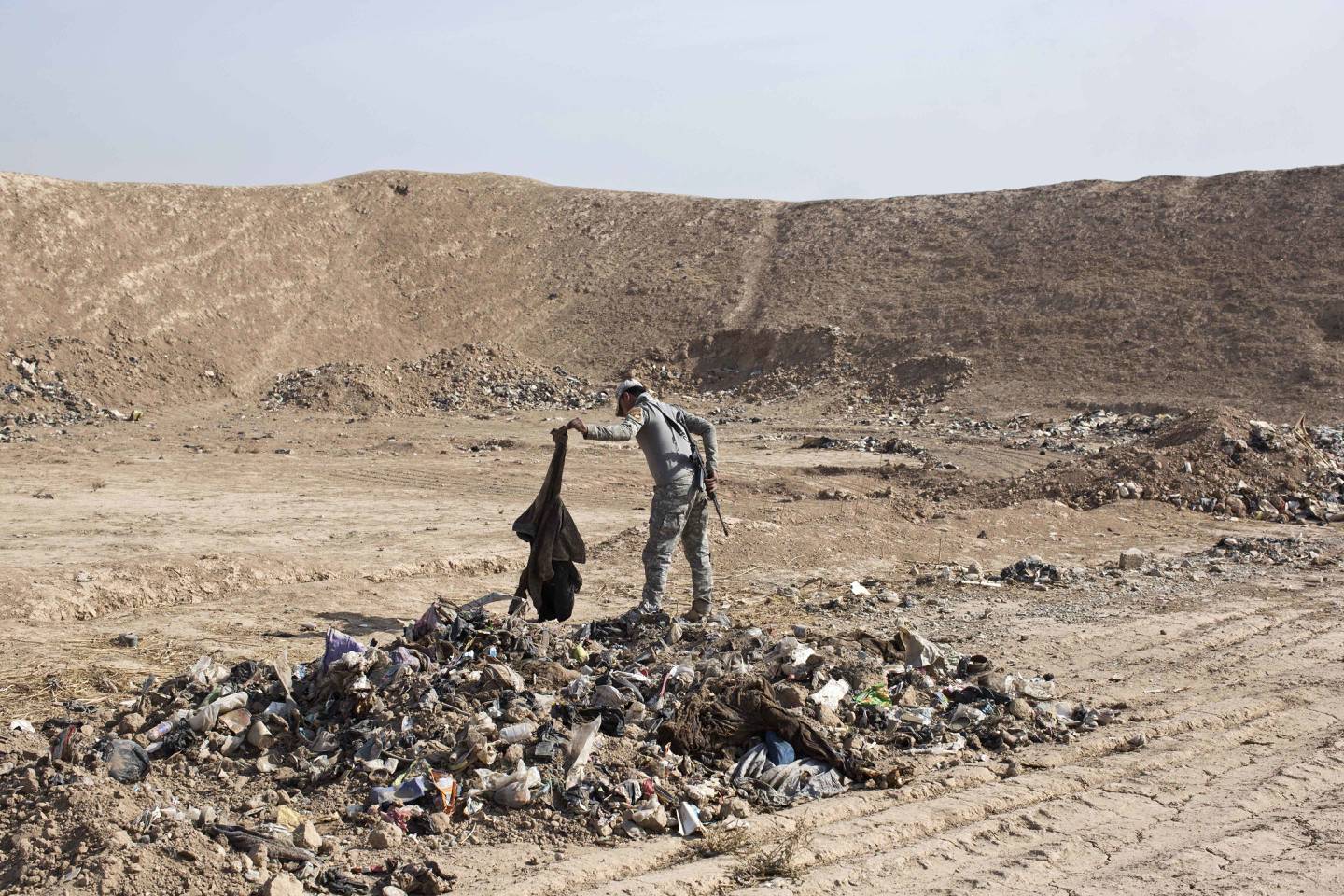 An Iraqi Federal Police officer examines human remains at a site of a mass grave of victims of Islamic State militants in Hamam al-Alil, some 10 kilometers south of Mosul, Iraq, Friday, Nov. 11, 2016. Iraqi troops inched ahead in their battle to retake the northern city of Mosul from the Islamic State group on Friday, as the U.N. revealed fresh evidence that the extremists have used chemical weapons. (AP Photo/Marko Drobnjakovic)