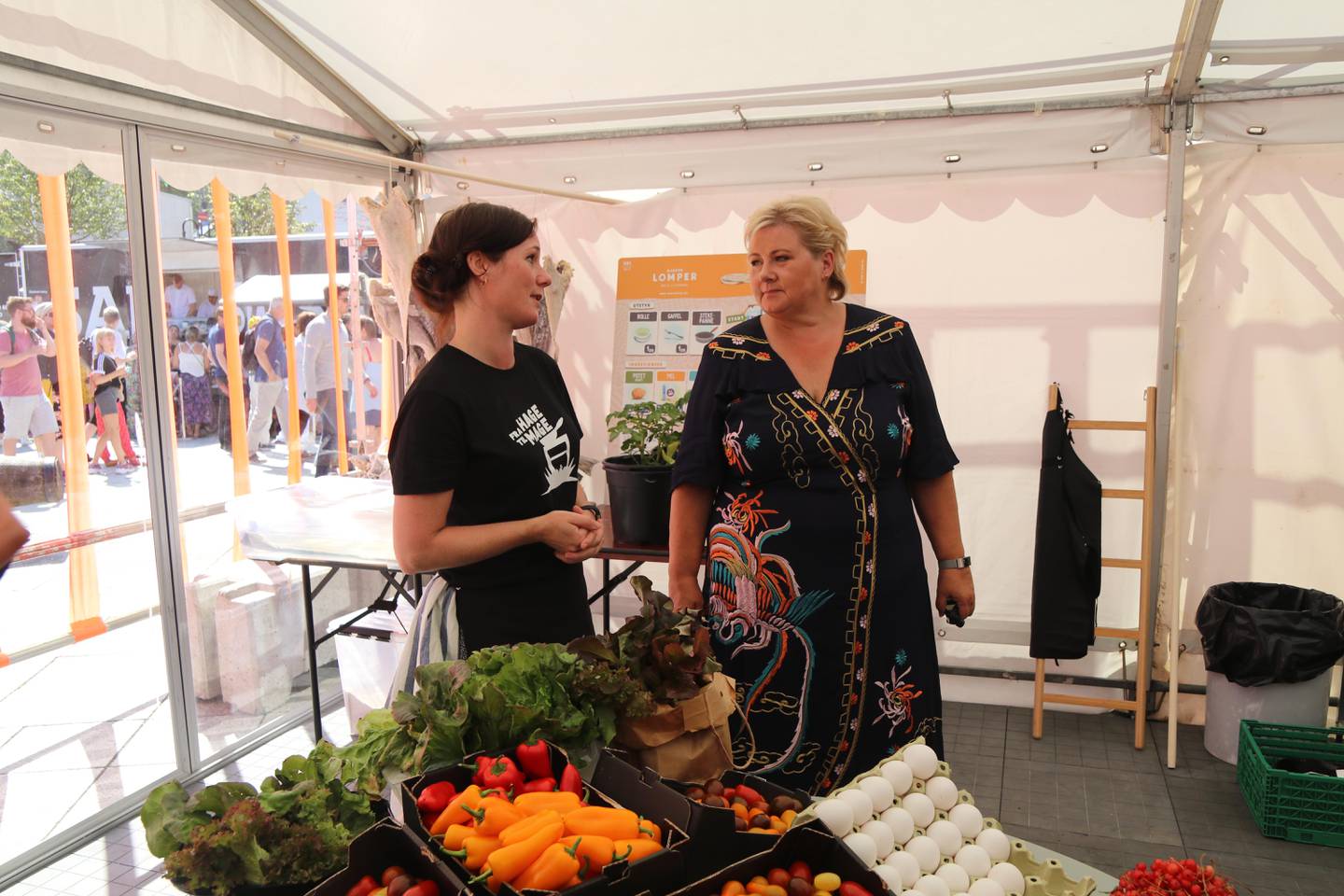 Daglig leder i Fra Hage til Mage, Therese D'Este Thomassen, viser statsminister Erna Solberg rundt i teltet hvor det arrangeres kokkekurs for barn.