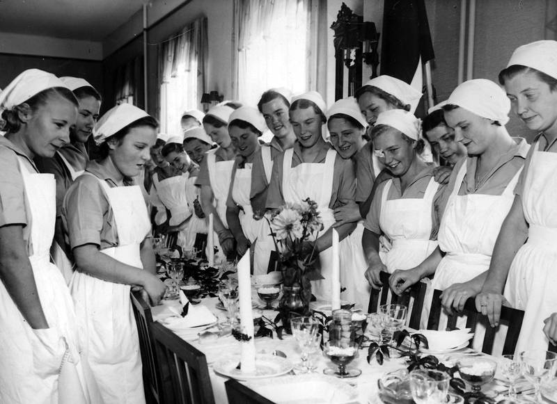 Innvielsesfesten for høstsemesteret 1936. Elever ved Husmorskolen kledd i påkrevde hvite forklær og skaut over oppsatt hår.