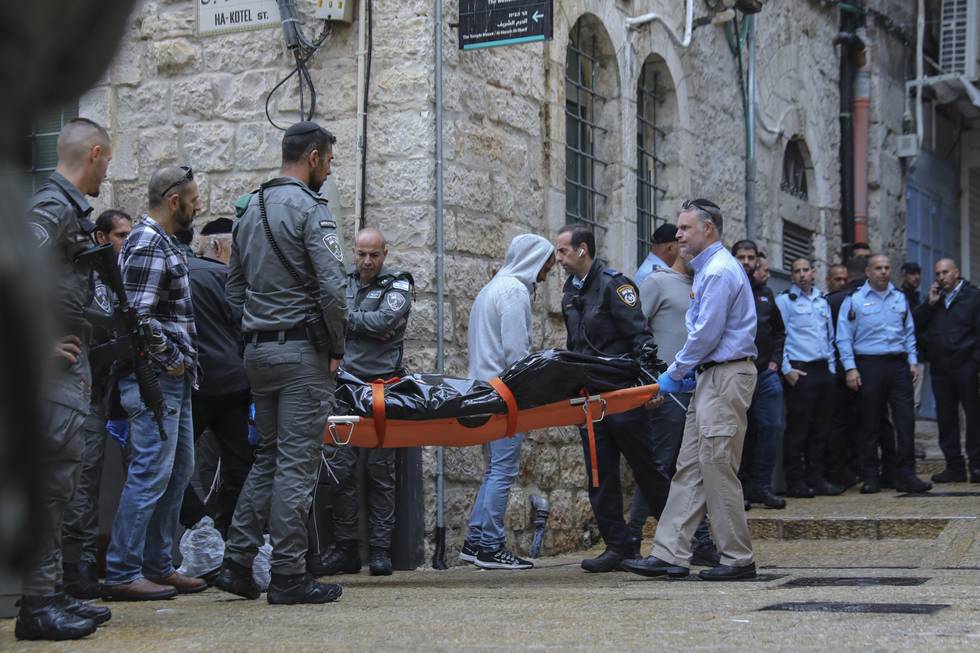 Israelske sikkerhetsstyrker og ambulansepersonell bærer bort palestineren som ble skutt og drept av politiet etter at han drepte en israeler og såret minst tre andre i gamlebyen i Jerusalem. Foto: Mahmoud Illean / AP / NTB