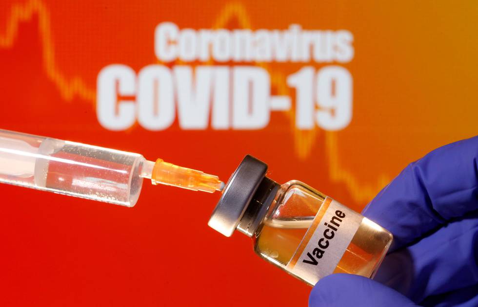 FILE PHOTO: A small bottle labeled with a "Vaccine" sticker is held near a medical syringe in front of displayed "Coronavirus COVID-19" words in this illustration taken April 10, 2020. REUTERS/Dado Ruvic/Illustration/File Photo