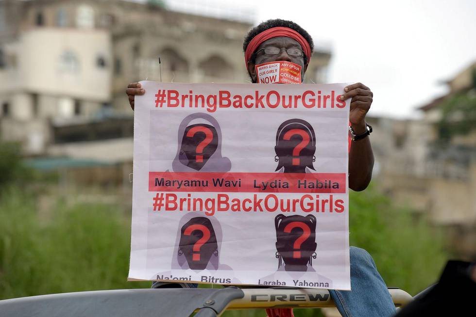 A supporter of the #BringBackOurGirls campaign carries a placard showing the missing faces of the kidnapped Chibok schoolgirl during a demonstration in the Nigerian capital Abuja on October 14, 2014.  Nigerian police on Tuesday blocked supporters of 219 schoolgirls kidnapped by Boko Haram militants from marching on the president's official residence on the six-month anniversary of the abduction. A wall of female officers in full riot gear formed the first line of a barricade in front of less than 100 members of the Bring Back Our Girls campaign, preventing them from setting out.AFP PHOTO/PIUS UTOMI EKPEI