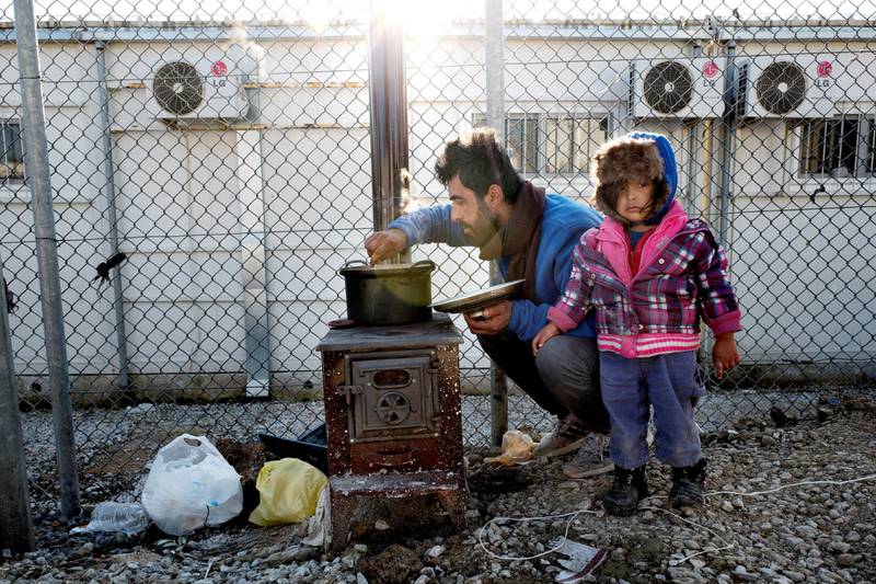 En far og datter lager mat utenfor teltet deres i Moria-Leiren. Far Kamal Allakbar Fattahi (32 år) og datter Asia på tre er iranske kurdere, født i Irak, og viser fram kopien av et dokument fra UNHCR som erklærer at de har flyktningstatus og har behov for hjelp.