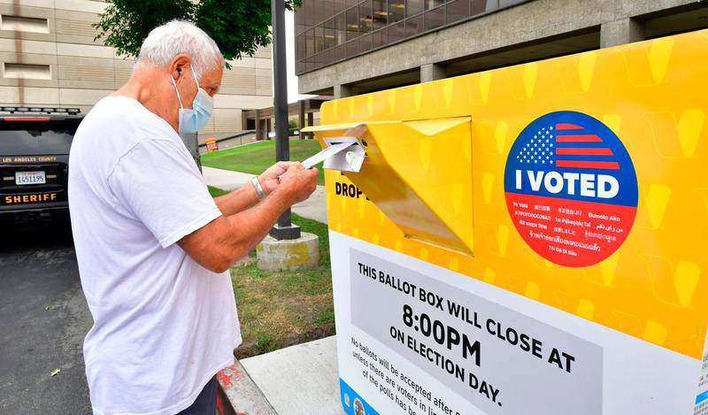 A voter drops his ballot for the 2020 US elections into an official ballot drop box at the Los Angeles County Registrar in Norwalk, California on October 19, 2020. - Voter turnout is ten times higher than in 2016 in California according the Secretary of State Alex Padilla as over 600,000 Los Angeles County ballots are already at the county registrar. (Photo by Frederic J. BROWN / AFP)
