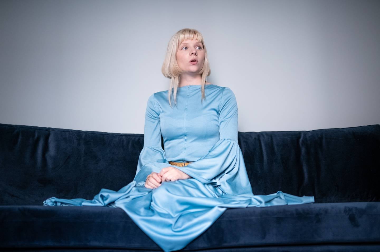 I en blå velursofa, og i blå kjole, sitter Aurora Aksnes.