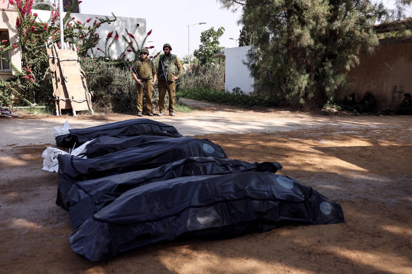 Israelske soldater holder vakt over noen av de døde i kibbutzen Kfar Aza, som ble angrepet av Hamas.