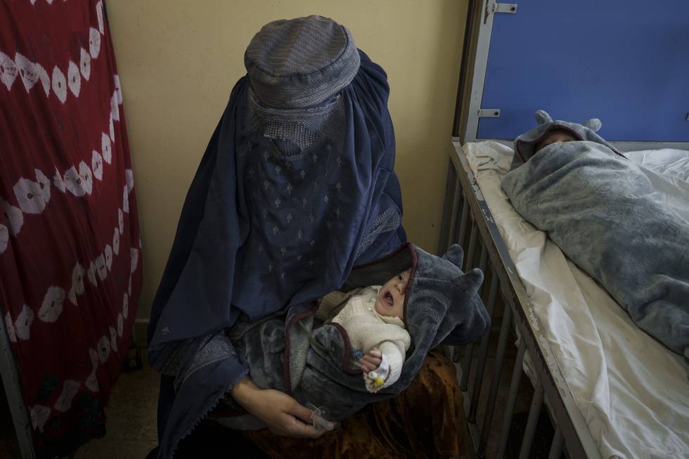 A woman holds one of her two babies undergoing treatment at the malnutrition ward of the Indira Gandhi Children's Hospital in Kabul, Afghanistan, Tuesday, Oct. 5, 2021. Health workers in the hospital dashed back and forth caring for gasping premature newborns and others suffering from severe malnutrition and other diseases. (AP Photo/Felipe Dana)