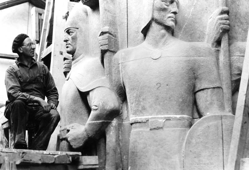 Under arbeidet med søylen benyttet Rasmussen seg av flere assistenter. Personen på bildet er ukjent, men mest sannsynlig en av steinhuggerne. Foto er fra atelieret i Nedregate 5 på 1930-40-tallet.
