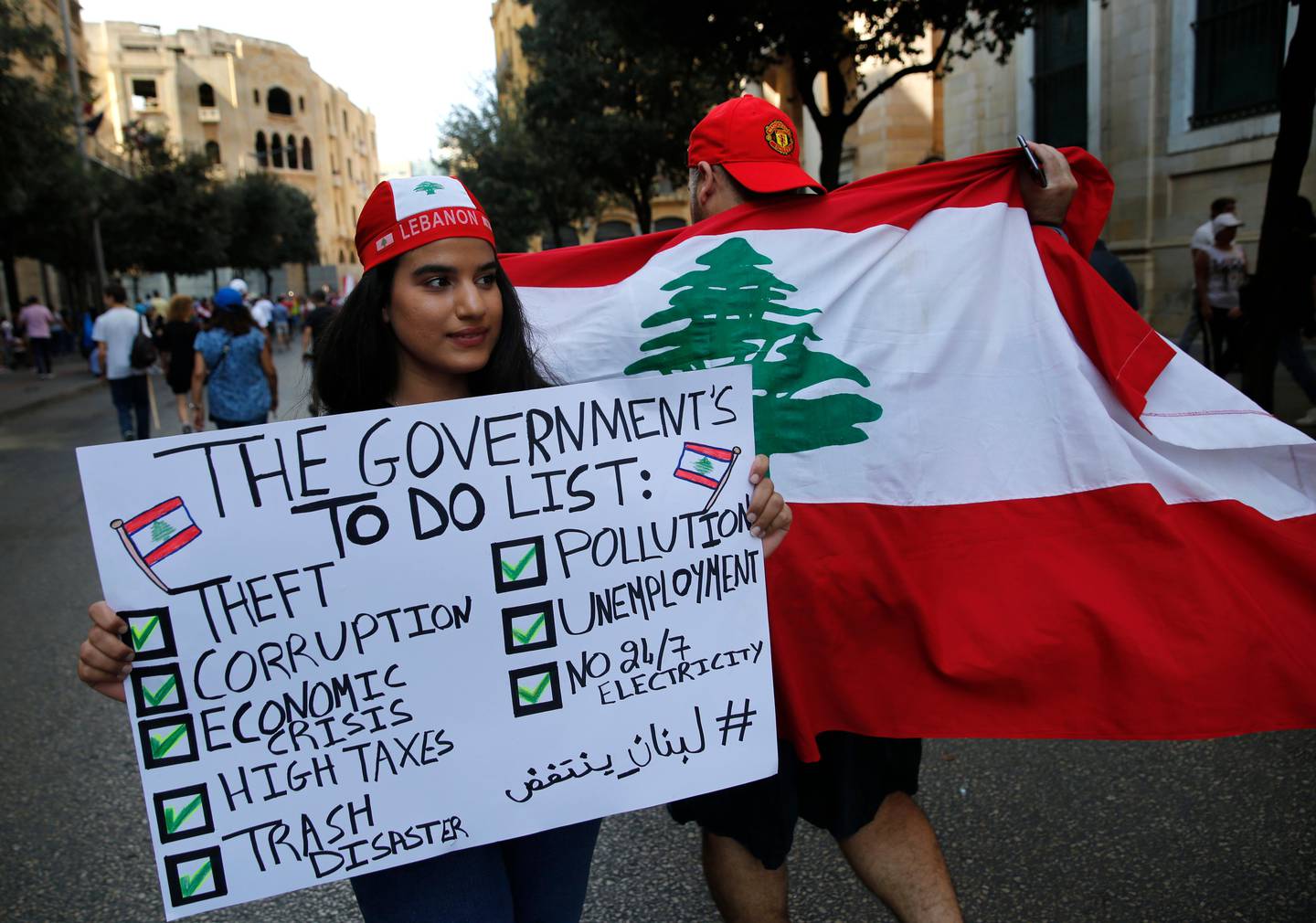 Protesters hold banners during a demonstration in Beirut, Lebanon, Sunday, Oct. 20, 2019. Protests erupted in Lebanon over the last couple of days after the government proposed new taxes criticized for hitting low-income groups the hardest. (AP Photo/Hussein Malla)