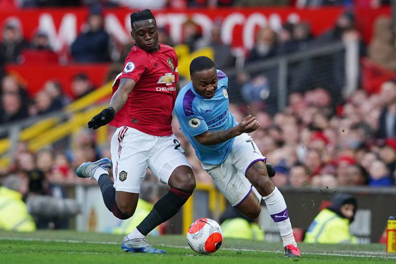 Manchester United's Aaron Wan-Bissaka, left, and Manchester City's Raheem Sterling compete for the ball during the English Premier League soccer match between Manchester United and Manchester City at Old Trafford in Manchester, England, Sunday, March 8, 2020. (AP Photo/Dave Thompson)