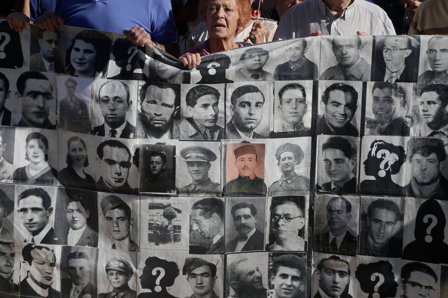 Protesters hold a banner showing photos of Spanish Civil War victims, outside the Supreme Court in Madrid, Spain, Tuesday, Sept. 24, 2019. The Spanish Supreme Court has ruled that the caretaker Socialist government can exhume the remains of former dictator Gen. Francisco Franco. Six judges met to decide on an appeal by Franco's relatives against the government plan to remove the body from the gigantic Valley of the Fallen mausoleum he built on the outskirts of Madrid and take it to a cemetery elsewhere. (AP Photo/Paul White)