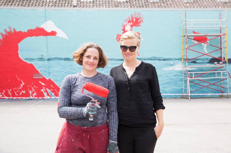 Kaja Olsen (til høyre), initiativtaker til det nye veggkunstprosjektet i Moss, med en av kunstnerne, Sandra Lockertsen. Hennes maleri skal vise tre kråker som flyr over Oslofjorden og inn mot Moss, med Bastøferga seilende under seg.