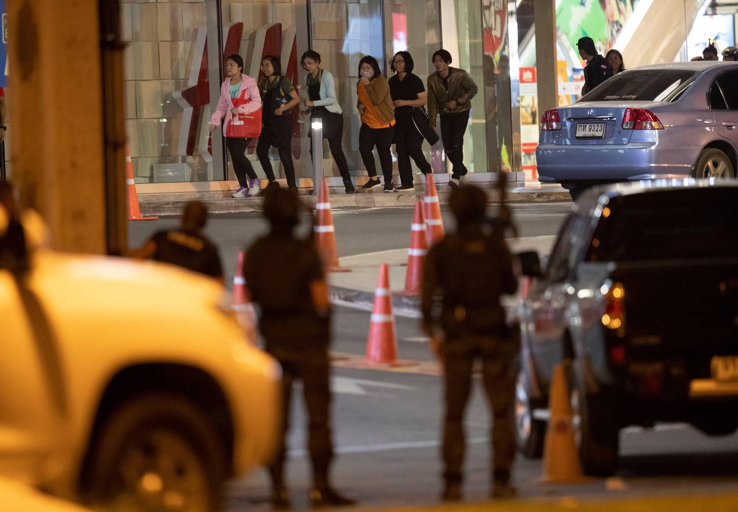 People who were able to get out of Terminal 21 Korat mall walk outside the building in Nakhon Ratchasima, Thailand on Sunday, Feb. 9, 2020. A soldier who holed up in a popular shopping mall in northeastern Thailand shot multiple people on Saturday, killing at least 20 and injuring 31 others, officials said. (AP Photo/Sakchai Lalitkanjanakul)
