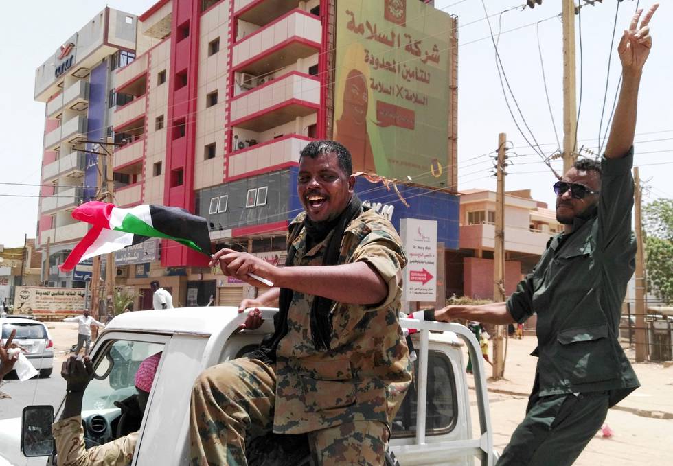 Members of the Sudanese security forces wave their national flag and flash the "V" for victory sign on April 11, 2019 in the capital Khartoum. - Huge crowds of jubilant Sudanese thronged squares and thoroughfares across the centre of Khartoum as the army promised an "important announcement" after months of protests, an AFP photographer reported. The crowds waved Sudanese flags and people hugged each other and exchanged sweets as they awaited the outcome of four months of protests demanding an end to President Omar al-Bashir's three decades of iron-fisted rule. (Photo by - / AFP)