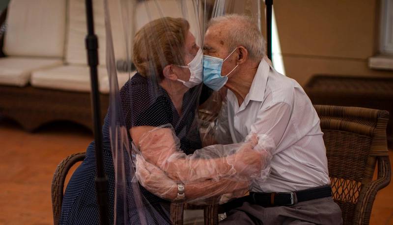 Agustina Canamero, 81, and Pascual Perez, 84, hug and kiss through a plastic film screen to avoid contracting the coronavirus at a nursing home in Barcelona, Spain, on June 22, 2020. Journalists from The Associated Press around the world assessed how the countries where they are posted have weathered the pandemic  and where those countries stand on the cusp of year two of the contagion. (AP Photo/Emilio Morenatti)