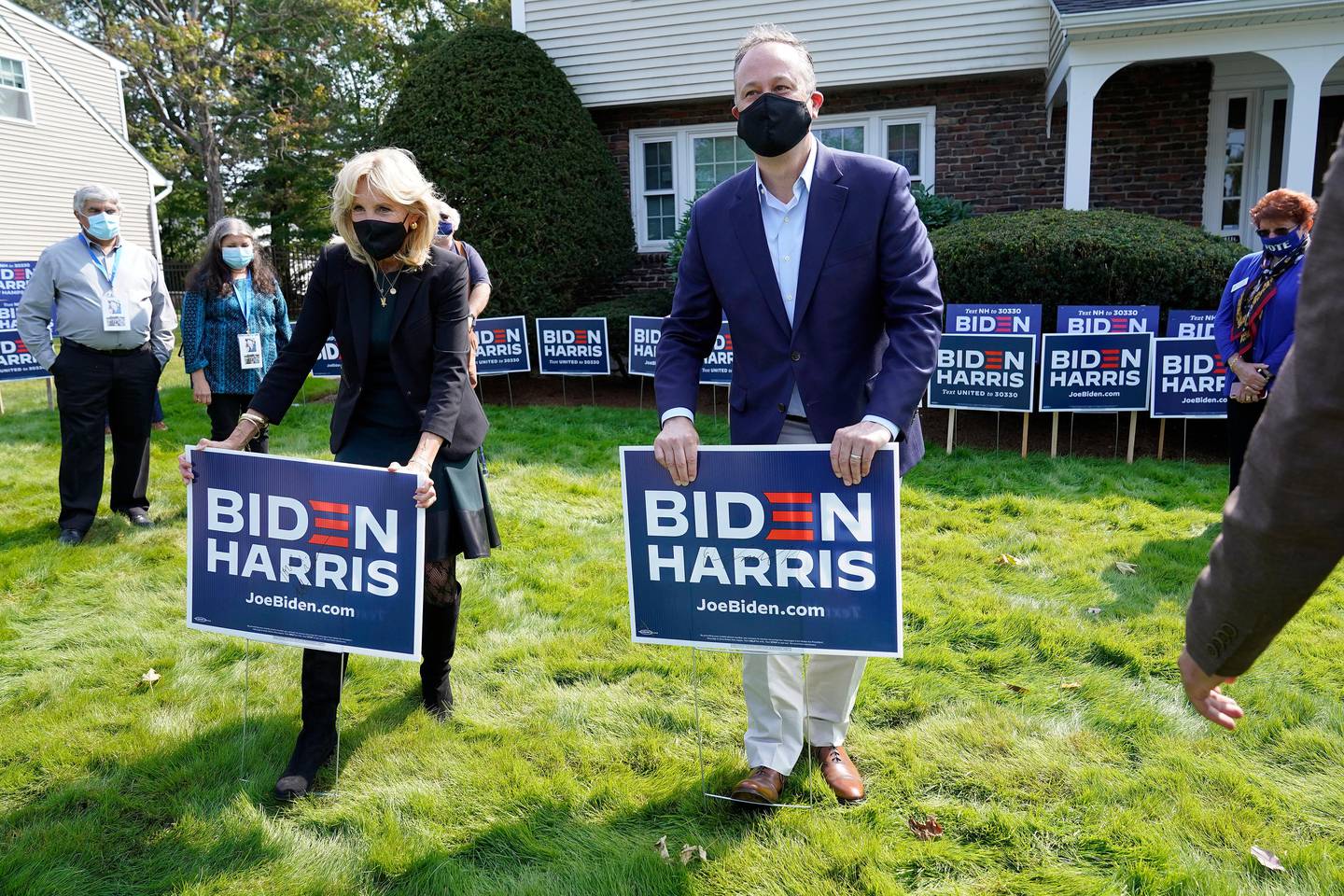 Jill Biden, front left, wife of Democratic presidential candidate former vice president Joe Biden, and Doug Emhoff, center, husband of Democratic vice presidential candidate Sen. Kamala Harris, D-Calif., place campaign placards into the ground during a campaign stop, Wednesday, Sept. 16, 2020, in Manchester, N.H. (AP Photo/Steven Senne)