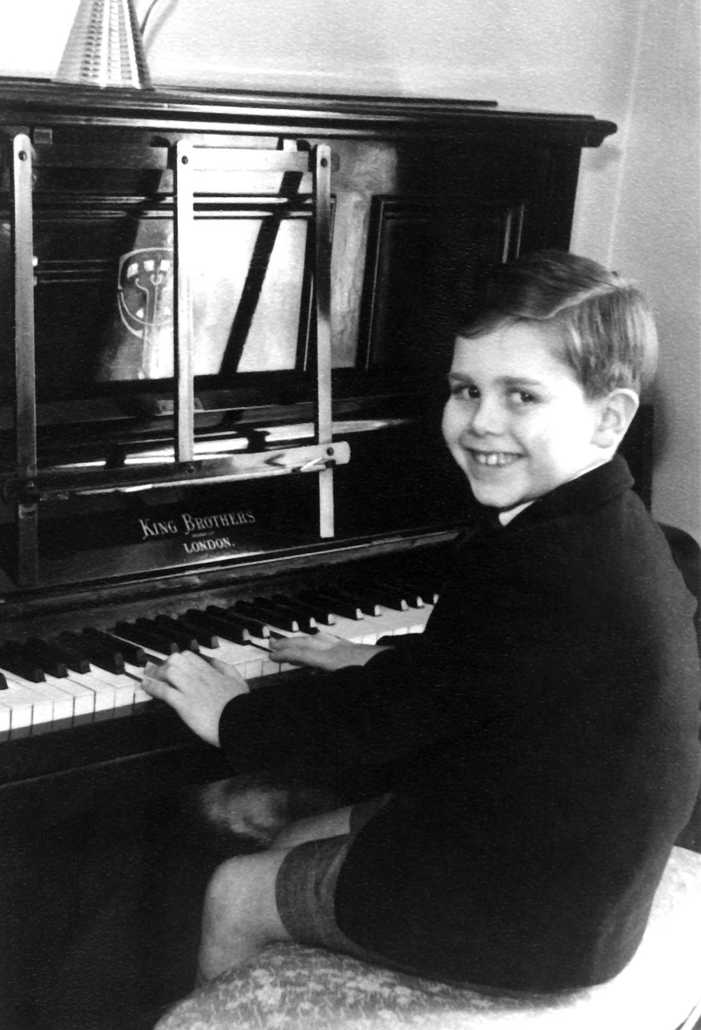Elton John ved familiens piano, som han fort lærte seg å spille på. Foto: Elton John family collection/Gyldendal