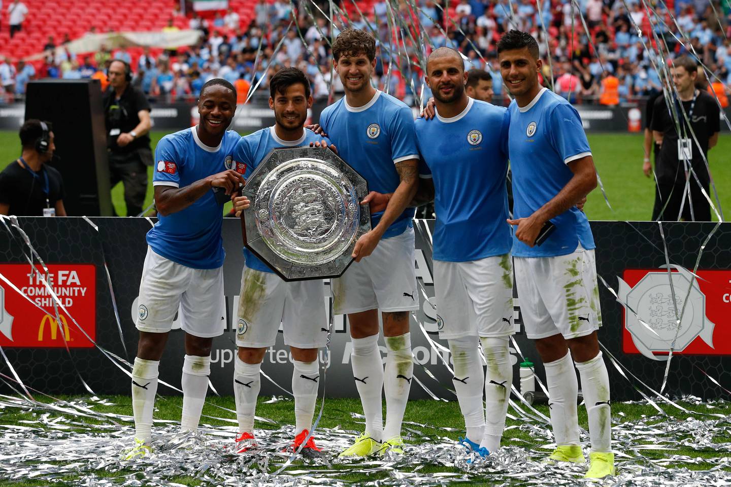 (L-R) Manchester City's English midfielder Raheem Sterling, Manchester City's Spanish midfielder David Silva, Manchester City's English defender John Stones, Manchester City's English defender Kyle Walker and Manchester City's Spanish midfielder Rodrigo pose with the trophy after winning the English FA Community Shield football match between Manchester City and Liverpool at Wembley Stadium in north London on August 4, 2019. (Photo by Ian KINGTON / AFP) / NOT FOR MARKETING OR ADVERTISING USE / RESTRICTED TO EDITORIAL USE