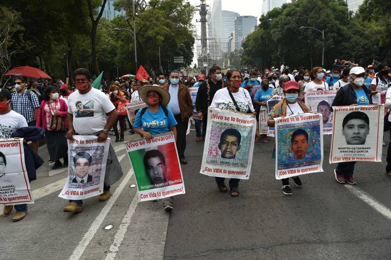 People protest during a protest in Mexico City on September 26, 2020, to mark six years of the disappearance of the 43 students of the teaching training school in Ayotzinapa who went missing on September 26, 2014. - The students, who had commandeered five buses to travel to a protest, were stopped by municipal police in the city of Iguala, Guerrero. Prosecutors initially said the officers delivered the 43 teacher trainees to drug cartel hitmen, who killed them, incinerated their bodies and dumped the remains in a river. However, independent experts from the Inter-American Commission on Human Rights have rejected the government's conclusion, and the unsolved case remains a stain on Mexico's reputation. (Photo by RODRIGO ARANGUA / AFP)