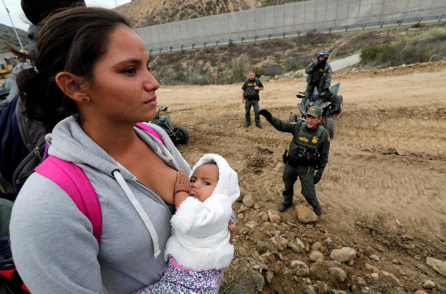 MED BARN: En migrant som er en del av karavanen holder babyen sin mens hun forsøker å krysse grensen ved Tijuana i Mexico. FOTO: NTB SCANPIX