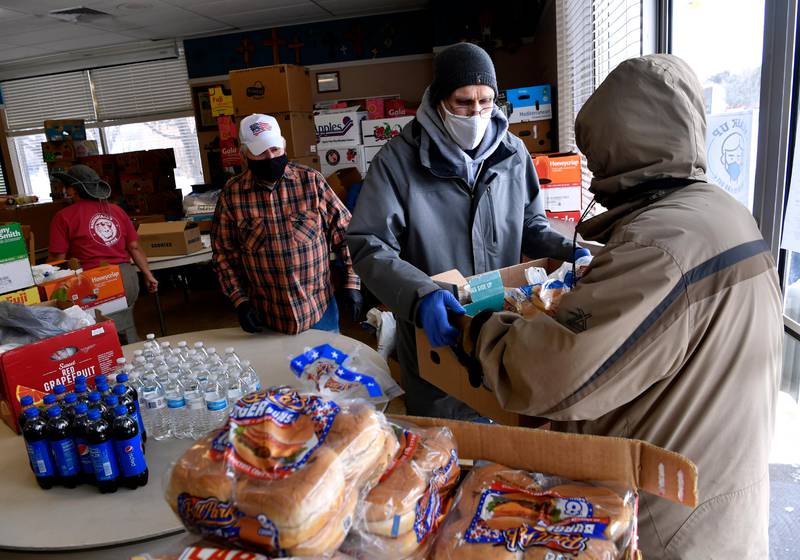 Bob Fink gives a box of food to a visitor to the City Light Community Ministries in Abilene, Texas Wednesday, Feb. 17, 2021. The kitchen normally provides food for those in need and was also operating a daytime warming center next door for those without power because of Sunday's record-breaking winter storm. (Ronald W. Erdrich/The Abilene Reporter-News via AP)