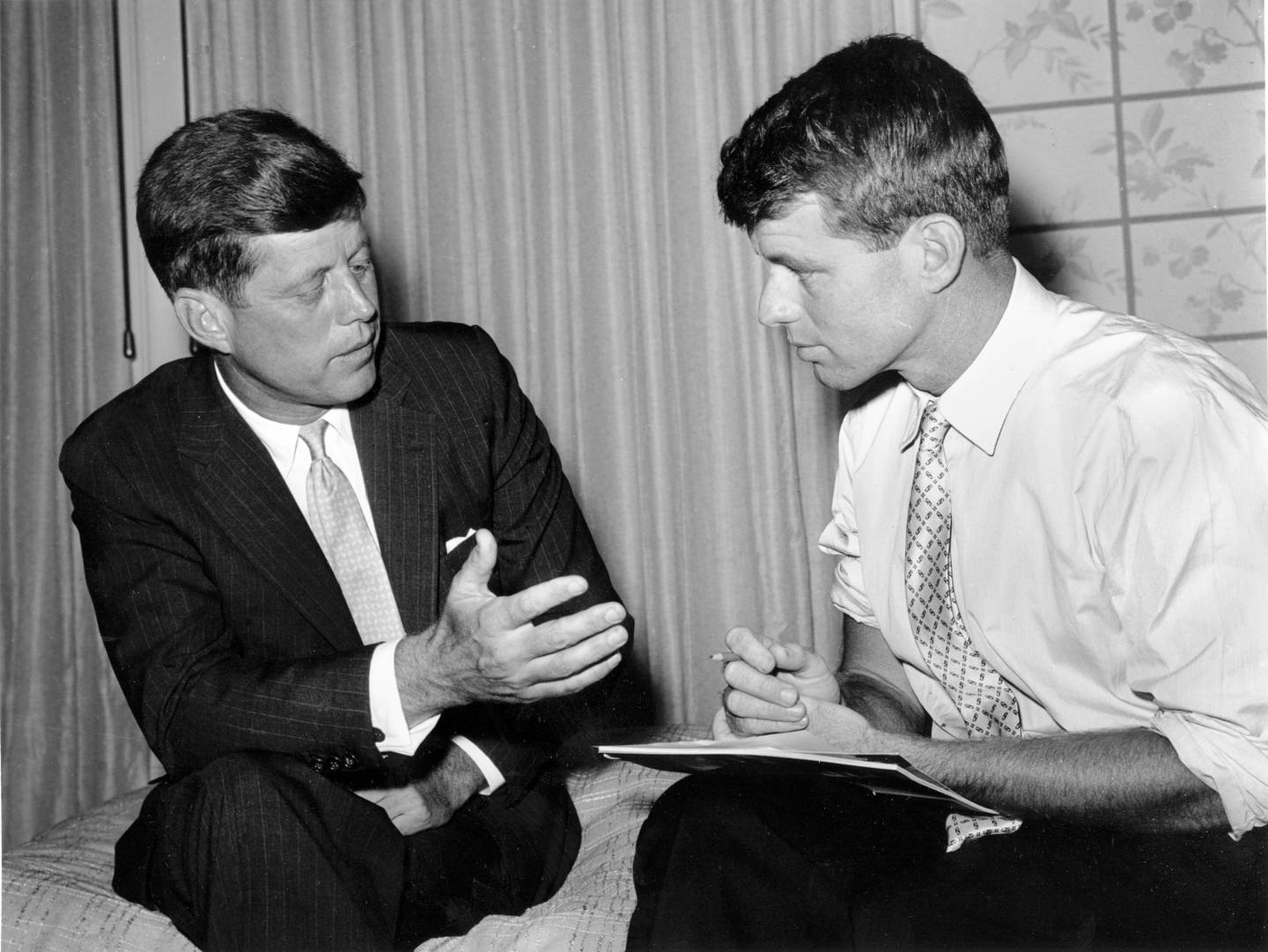 Massachusetts Sen. John F. Kennedy, left, compares notes with his brother and campaign manager, Robert Kennedy, on July 10, 1960 in an unknown location. The Senator is seeking the Democratic presidential nomination. (AP Photo)
