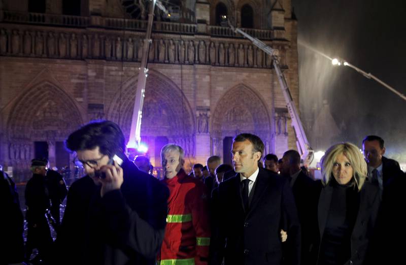 French President Emmanuel Macron, center, and his wife Brigitte walk away from Notre Dame cathedral in Paris, Monday, April 15, 2019. A catastrophic fire engulfed the upper reaches of Paris' soaring Notre Dame Cathedral as it was undergoing renovations Monday, threatening one of the greatest architectural treasures of the Western world as tourists and Parisians looked on aghast from the streets below.(Philippe Wojazer/Pool via AP)