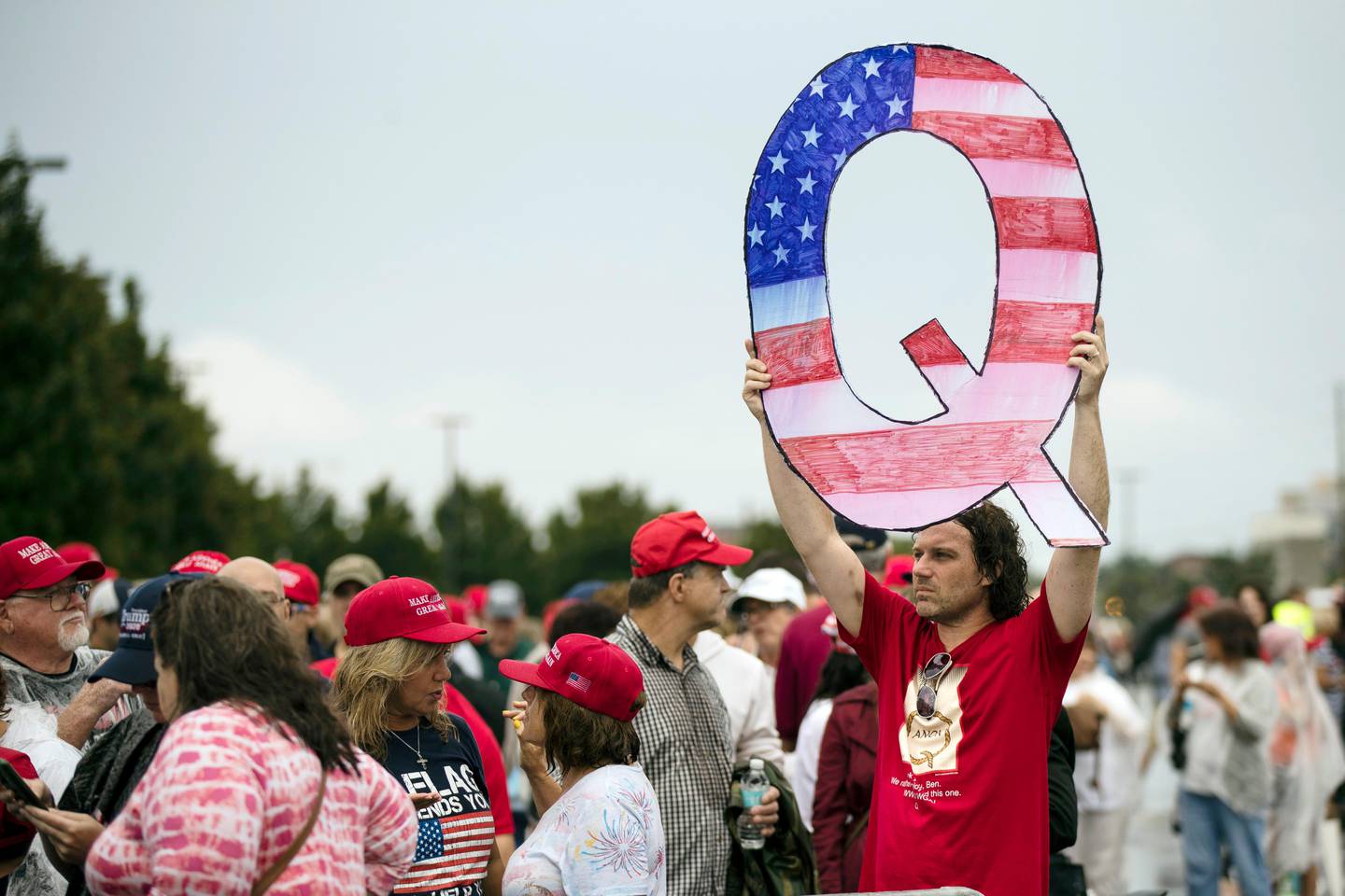FILE - In this Aug. 2, 2018, file photo, a protesters holds a Q sign waits in line with others to enter a campaign rally with President Donald Trump in Wilkes-Barre, Pa.   Facebook and Twitter promised to stop encouraging the growth of the baseless conspiracy theory QAnon, which fashions President Donald Trump as a secret warrior against a supposed child-trafficking ring run by celebrities and government officials. But the social media companies havent succeeded at even that limited goal, a review by The Associated Press found.  (AP Photo/Matt Rourke, File)