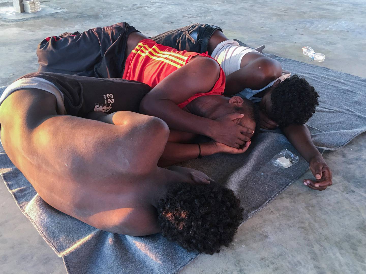 Rescued migrants rest on a coast some 100 kilometers (60 miles) east of Tripoli, Libya, Thursday, July 25, 2019. The U.N. refugee agency and the International Rescue Committee say up to 150 may have perished at sea off the coast of Libya. The country's coast guard says the Europe-bound migrants are missing and feared drowned after the boats they were traveling on capsized in the Mediterranean Sea. A spokesman says they rescued around 137 migrants on Thursday. (AP Photo/Hazem Ahmed)
