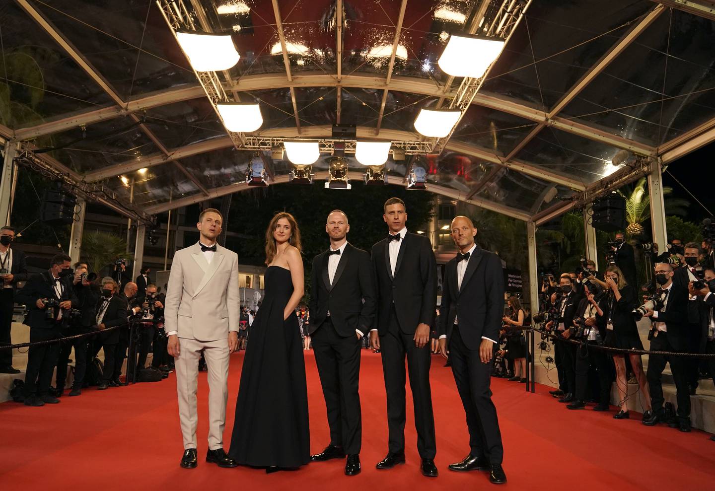 Teamet bak den norske filmen omkranset av fotografer i Cannes torsdag. Fra venstre: Anders Danielsen Lie, Renate Reinsve, Joachim Trier, Herbert Nordrum og Eskil Vogt. Foto: Brynn Anderson / AP / NTB