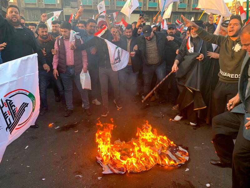 Protesters burn representations of a U.S. flag during a protest against the U.S. strikes on the Hezbollah Brigades militia, in Tahrir Square, Baghdad, Iraq, Monday, Dec. 30, 2019. The Iranian-backed militia said Monday that the death toll from U.S. military strikes in Iraq and Syria against its fighters has risen to 25, vowing to exact revenge for the "aggression of evil American ravens." (AP Photo/Ali Abdul Hassan)