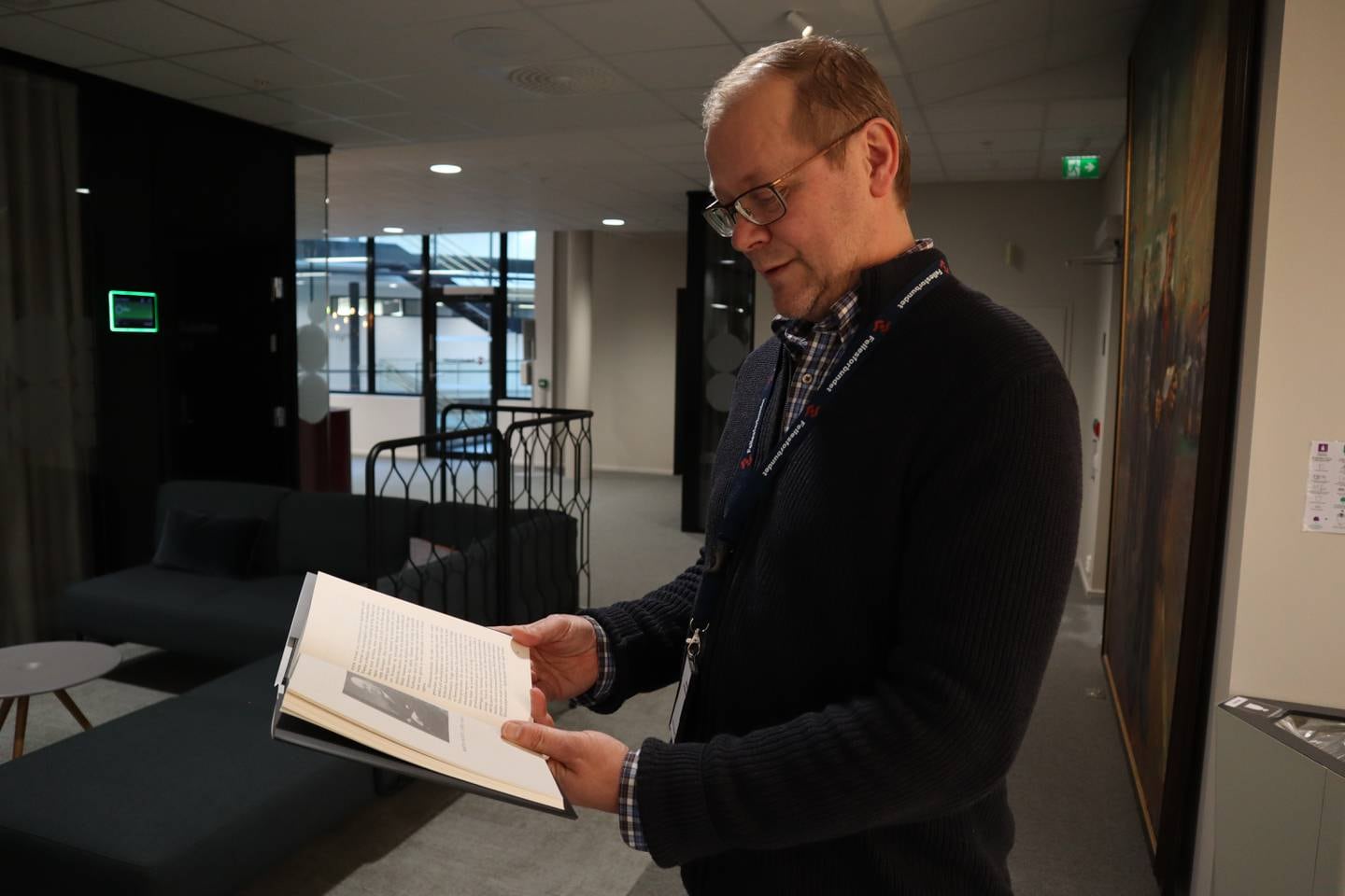 Kristian Ilner på 50 står på kontoret sitt og titter i boken sin.